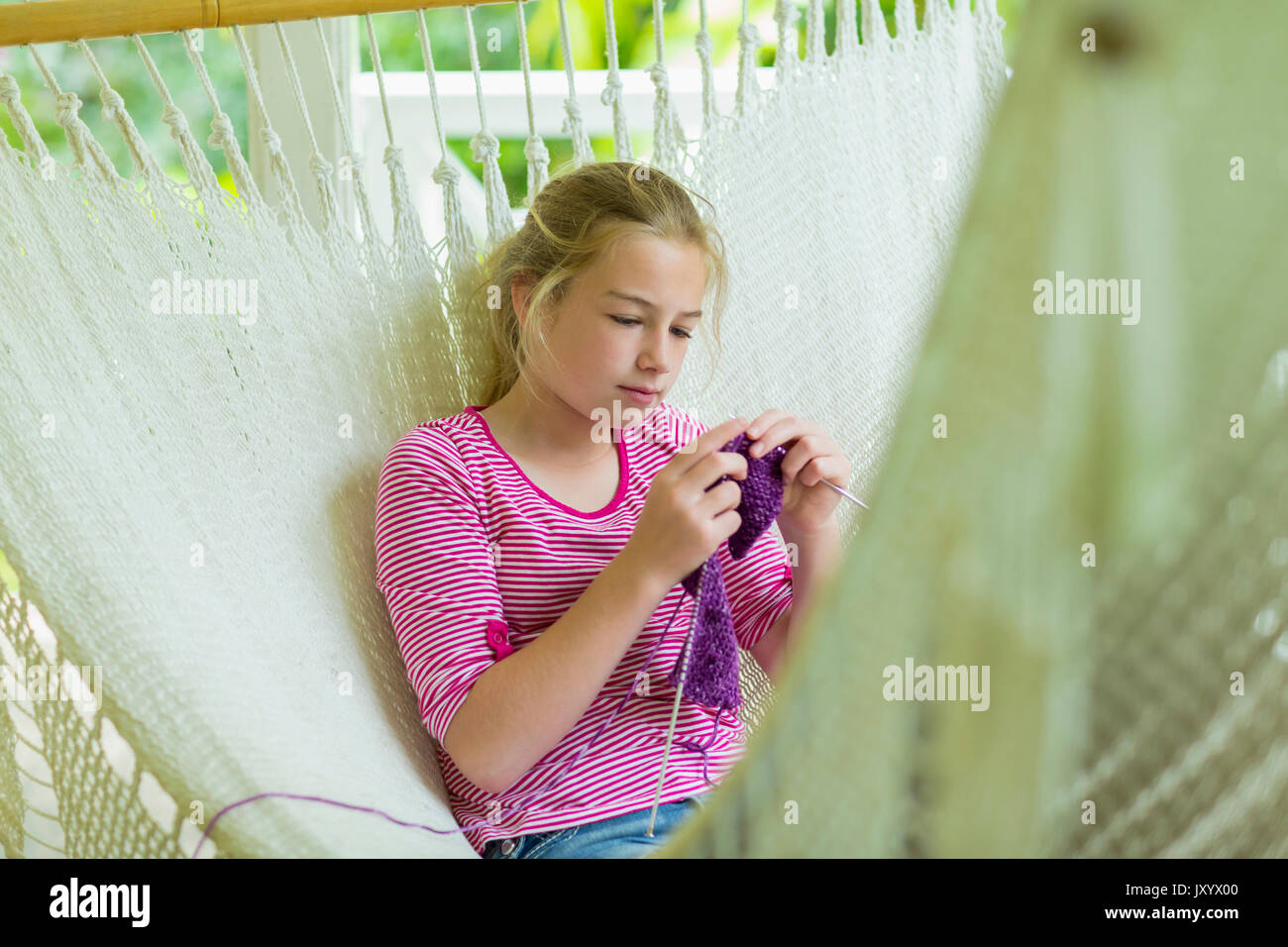 Caucasian girl laying in hammock and knitting Stock Photo