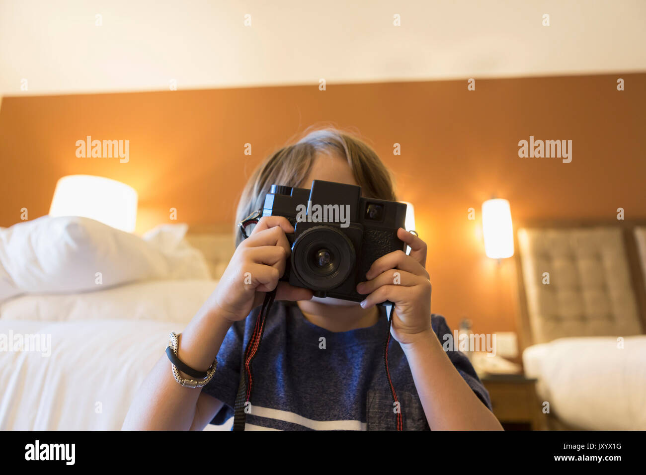 Caucasian boy photographing with camera in hotel room Stock Photo