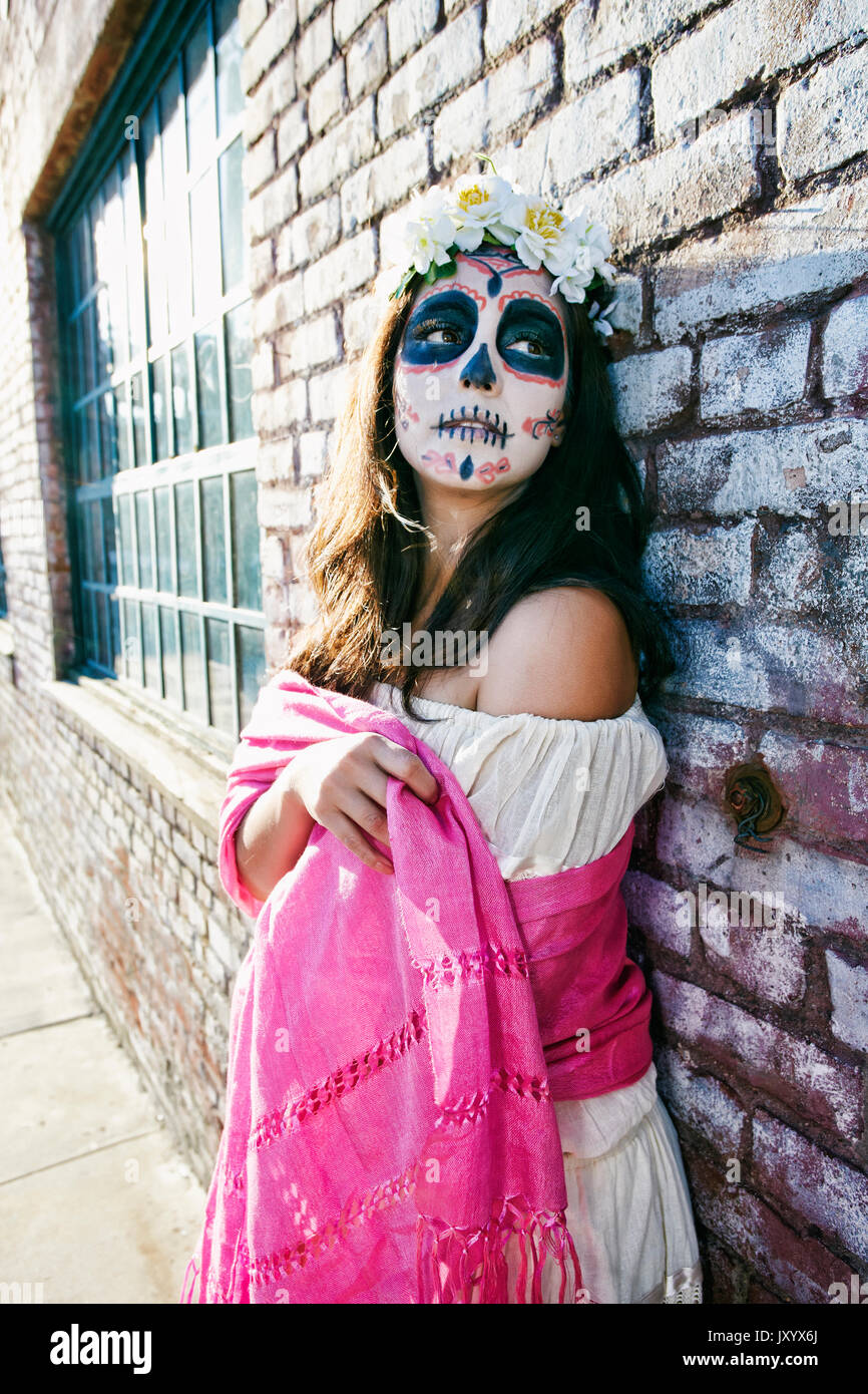 Mixed Race woman on sidewalk wearing skull face paint Stock Photo