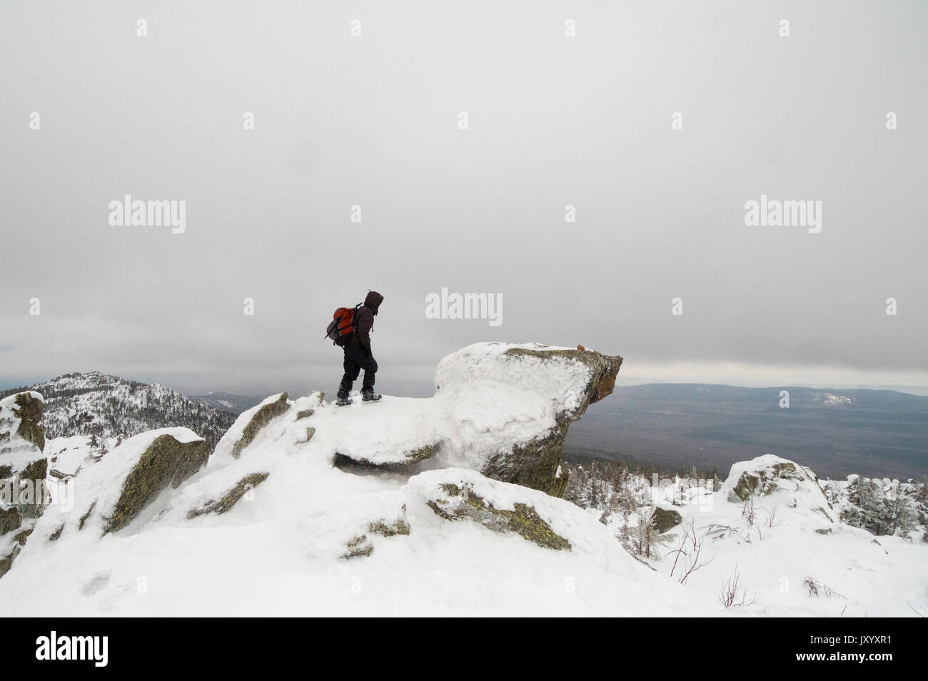 Distant Caucasian man standing on mountain in winter Stock Photo