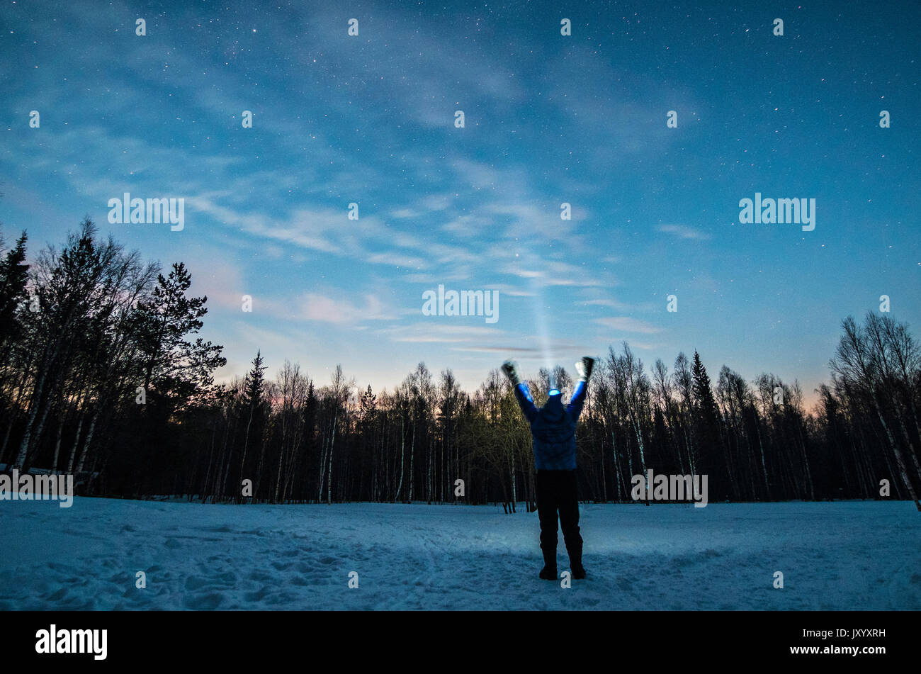 Caucasian man wearing headlamp with arms raised in winter Stock Photo