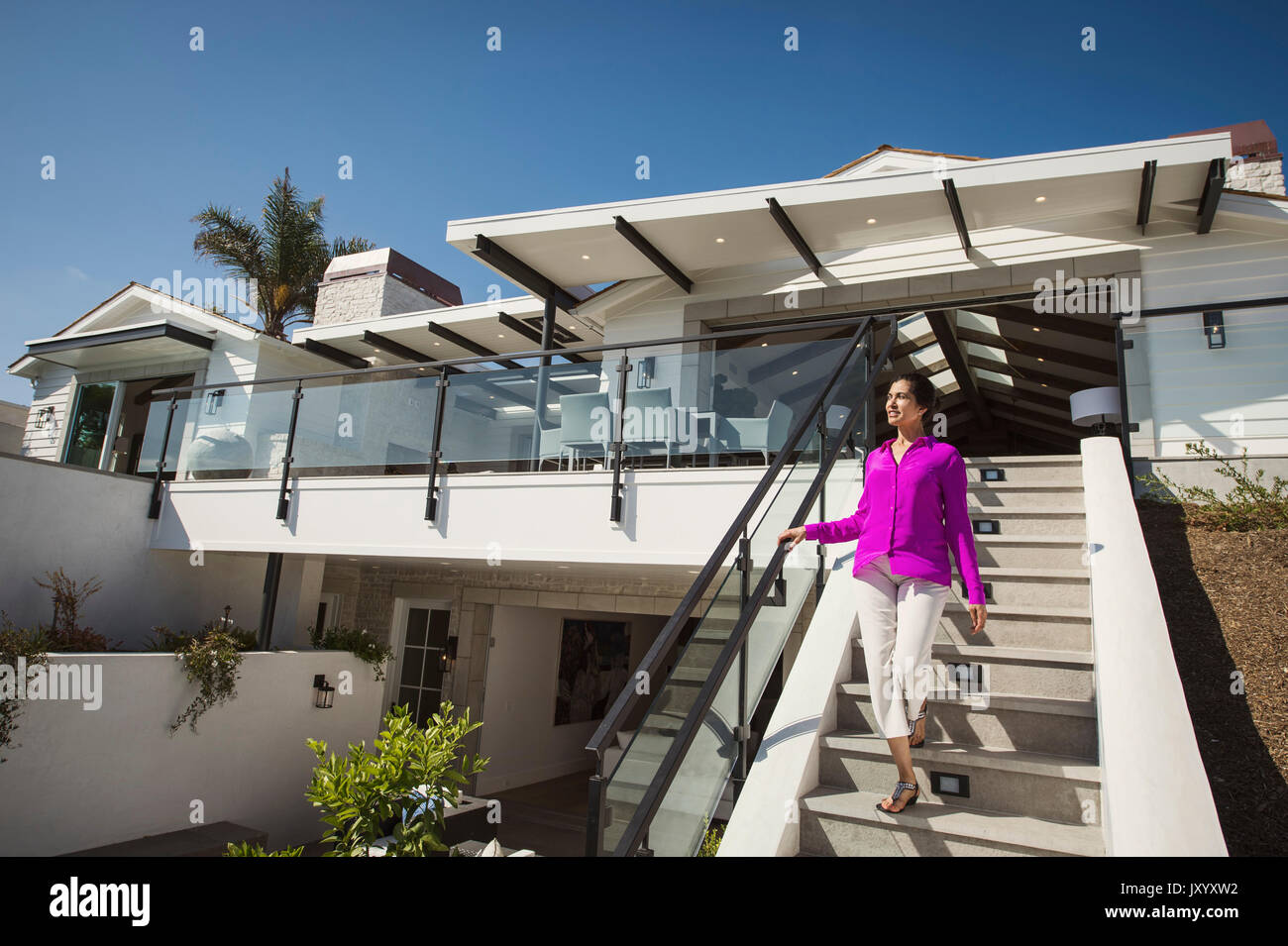 Hispanic woman walking on modern staircase Stock Photo