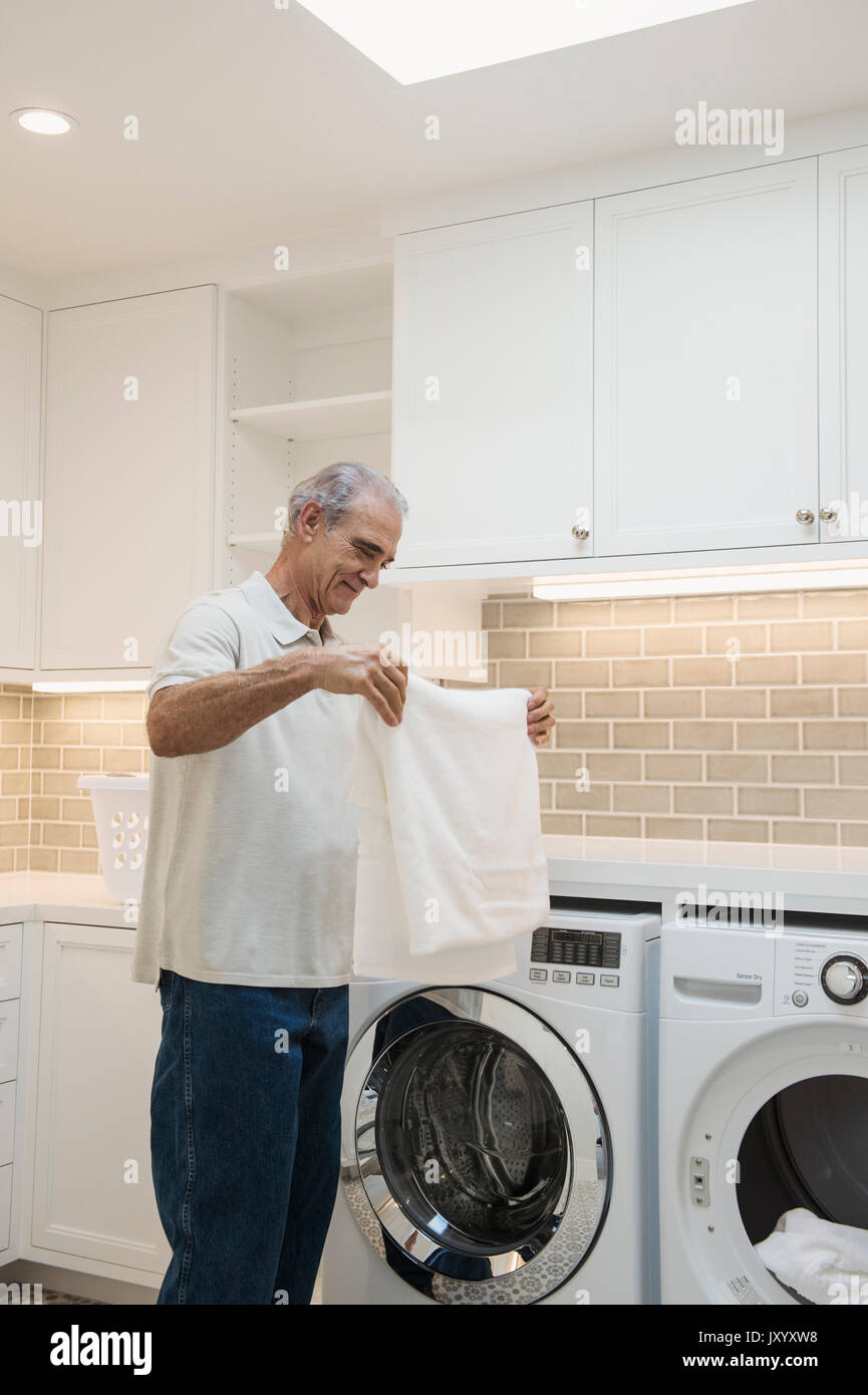 Caucasian man folding towel in modern laundry room Stock Photo