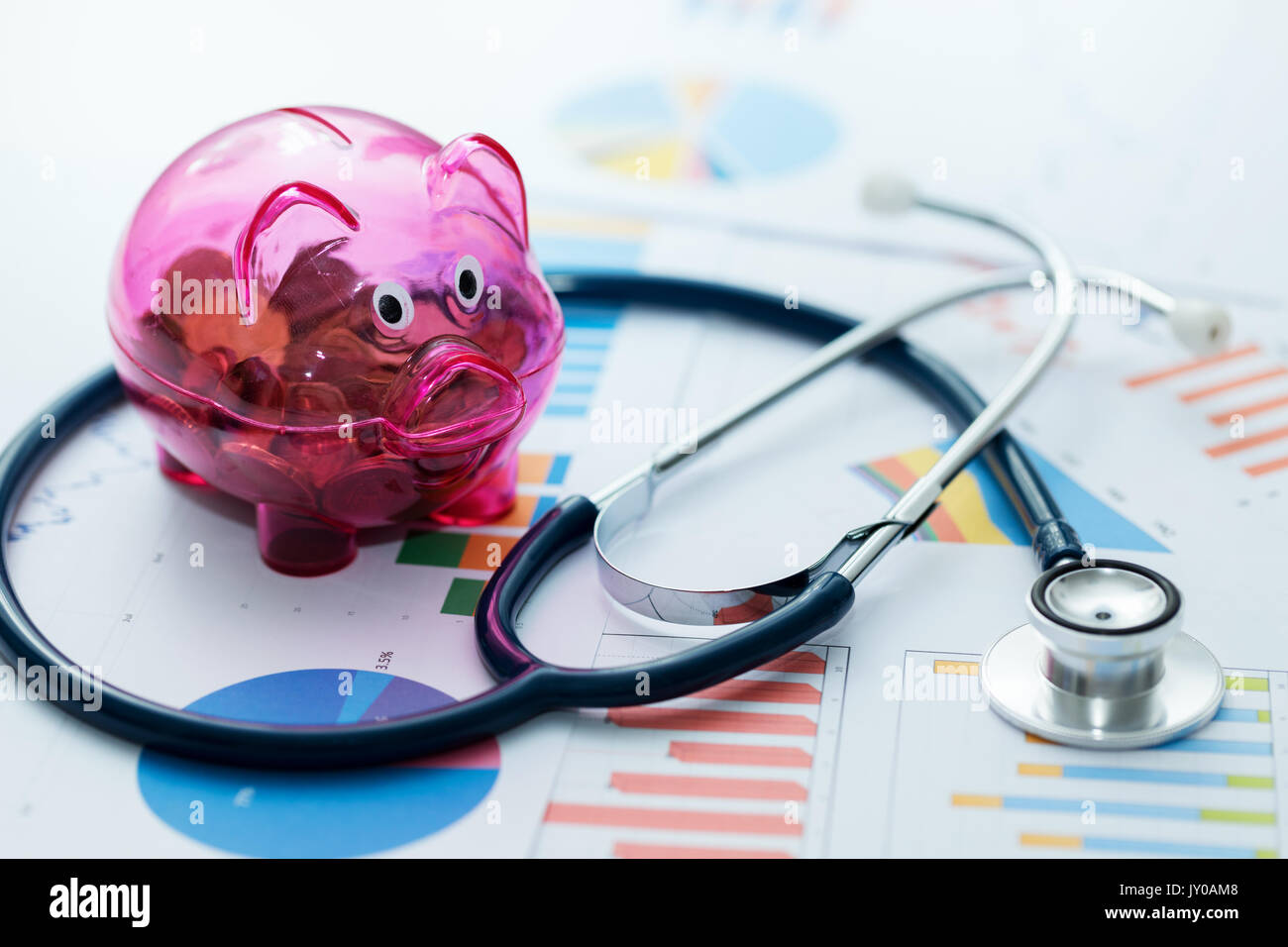 healthcare budget concept - stethoscope and piggy bank on graphic charts Stock Photo