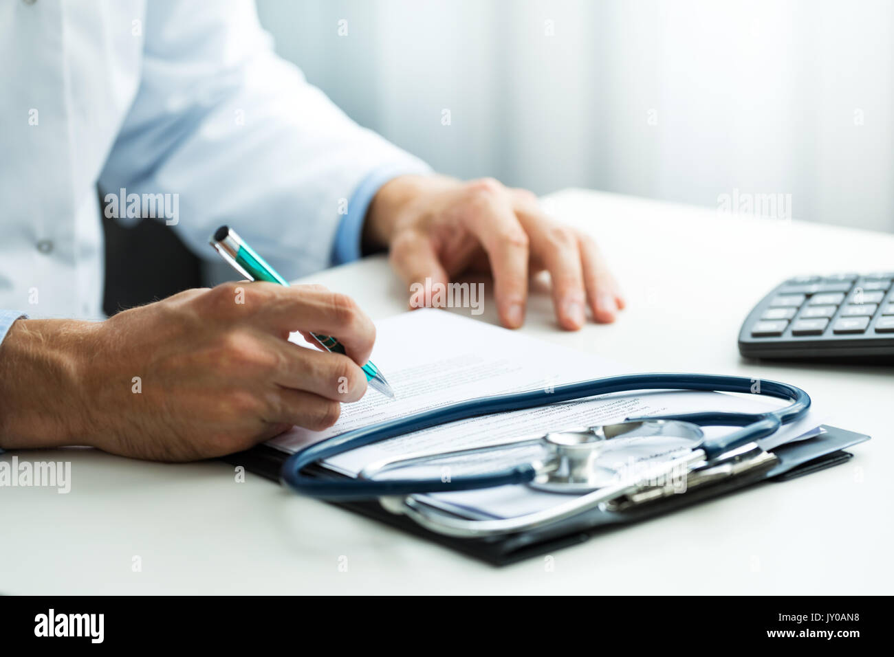 doctor writing prescription at desk in clinics office Stock Photo