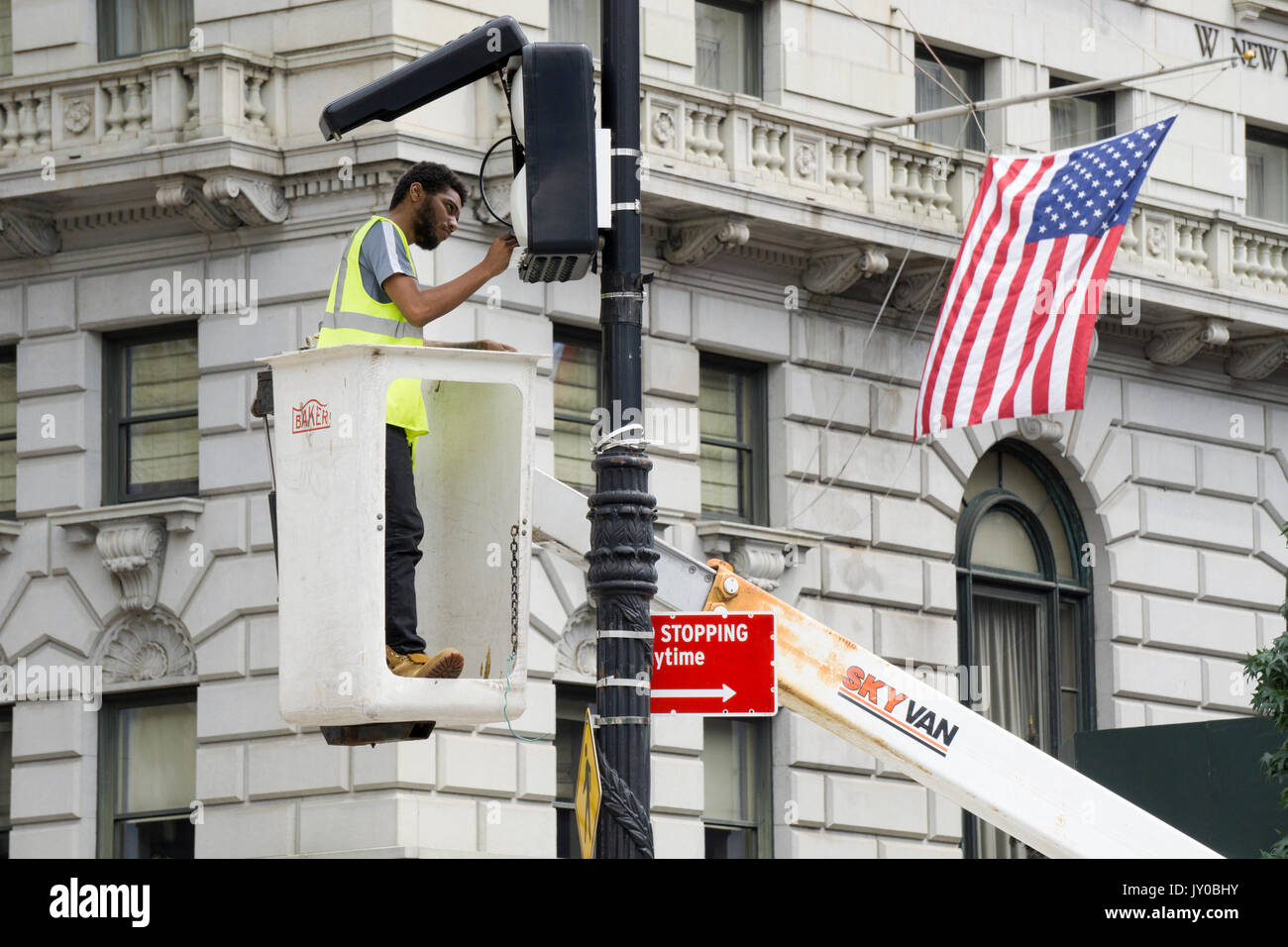 An electrician in a cherry picker repairing an AT&T wifi box near Union Square Park on Broadway in Manhattan. Stock Photo