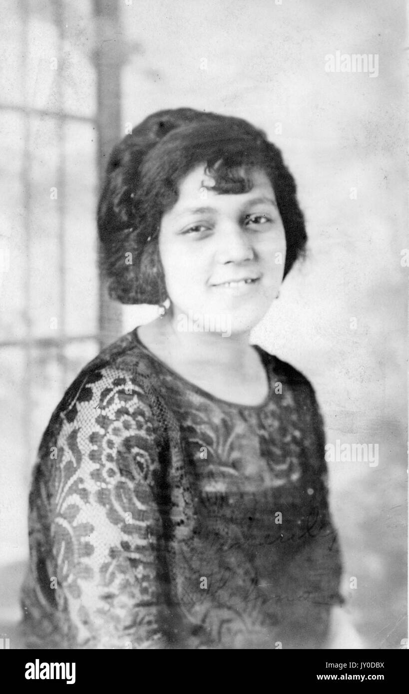 Half length portrait of a young African American woman, she is wearing a dark lace shirt and she is smiling, 1915. Stock Photo