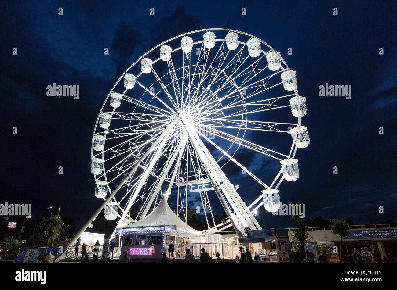 Bournemouth Big Wheel, Evening Fun on the seafront.  Zipwire with people sliding down from top of pier to sand in the sunshine on a lovely evening. Stock Photo