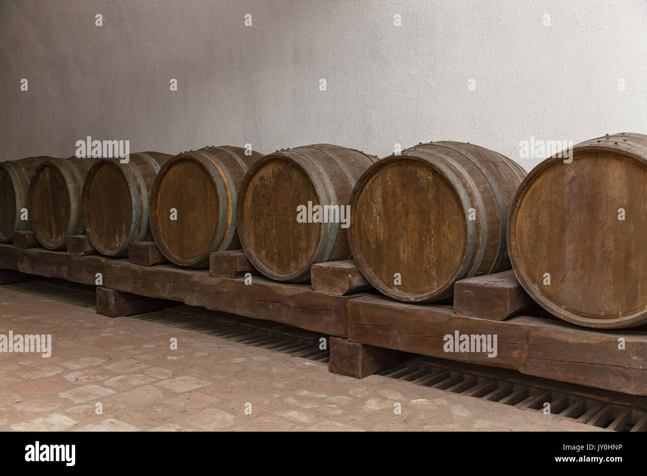 Old oak barrels lie in basement on wooden logs,old wine cellars with bottles and barrels Stock