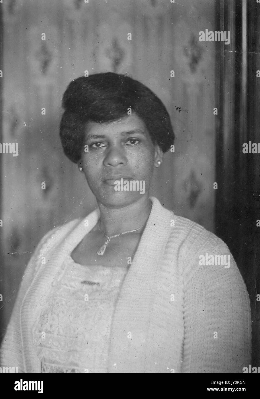 Headshot of mature African American woman, wearing light lace dress with light sweater, necklace and earrings, neutral expression, 1926. Stock Photo