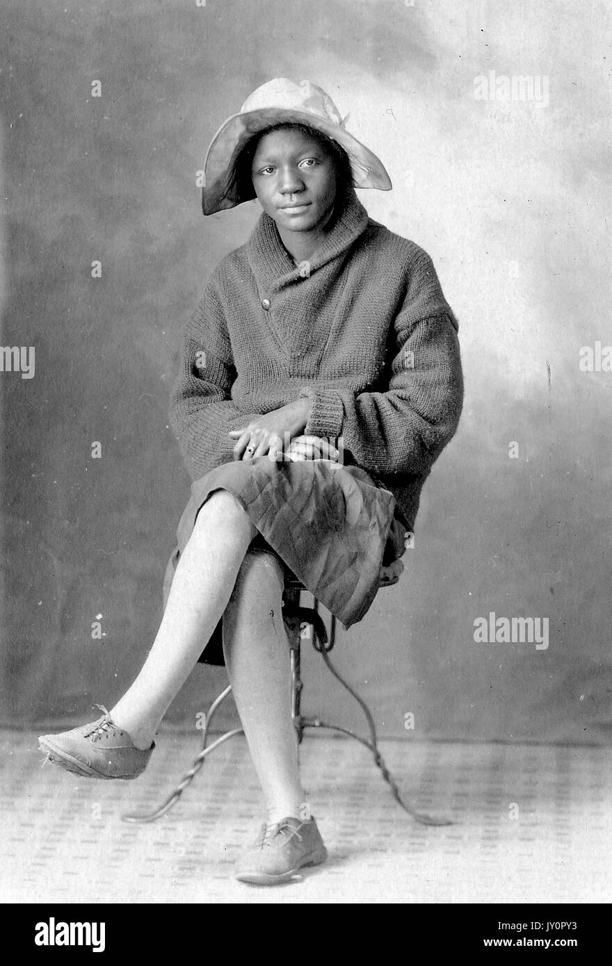 Full length sitting portrait, young African American woman sitting on a ...