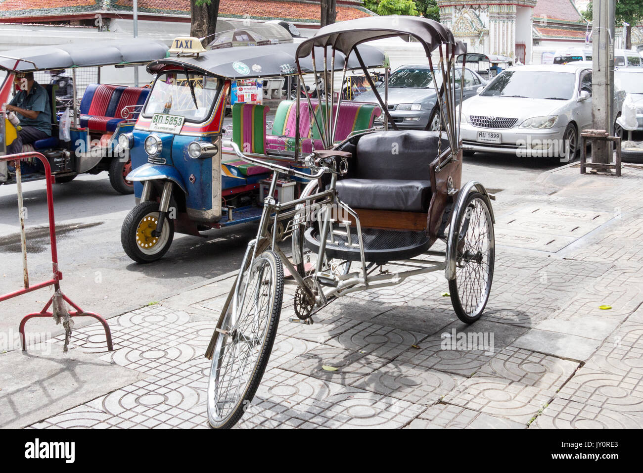 Rickshaw on pavement with tuk tuks in the background, Bangkok, Thailand Stock Photo