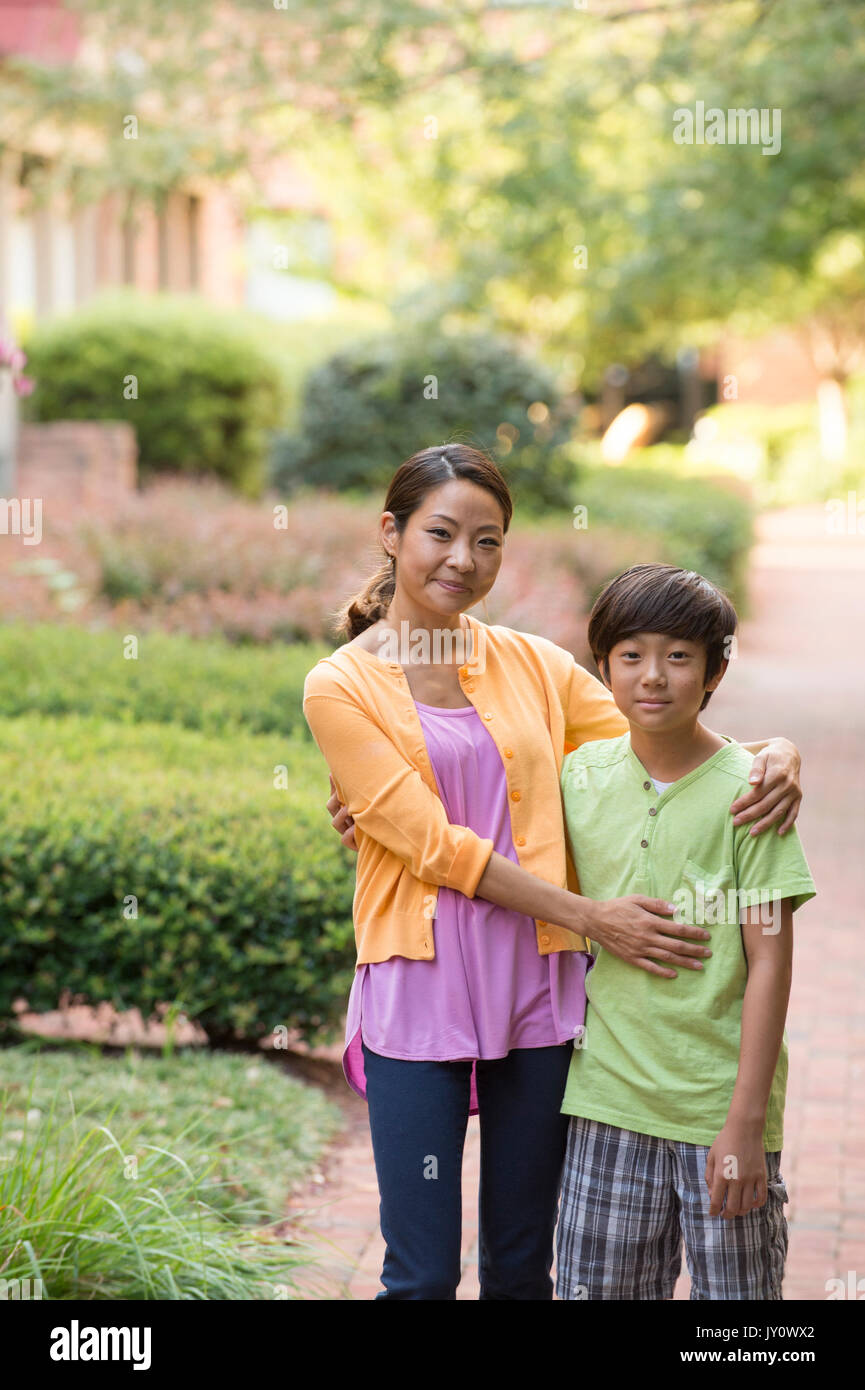 Portrait of Asian mother and son standing on sidewalk Stock Photo