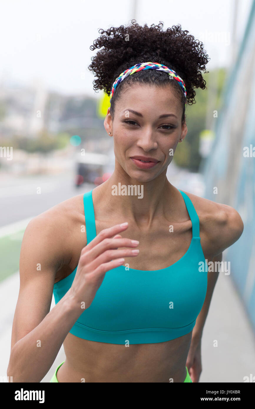 Mixed Race woman running on sidewalk Stock Photo