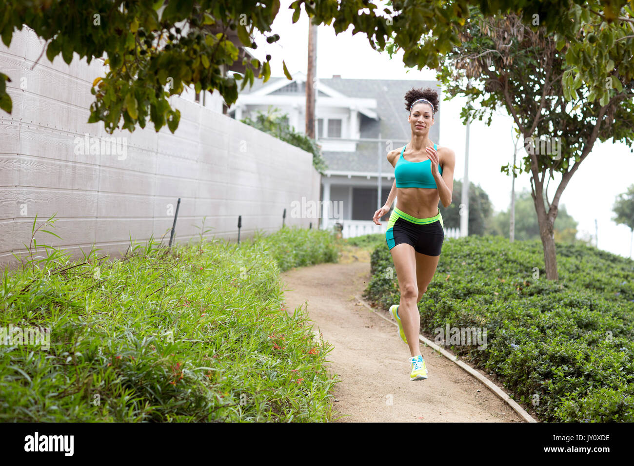 Mixed Race woman running on path in park Stock Photo