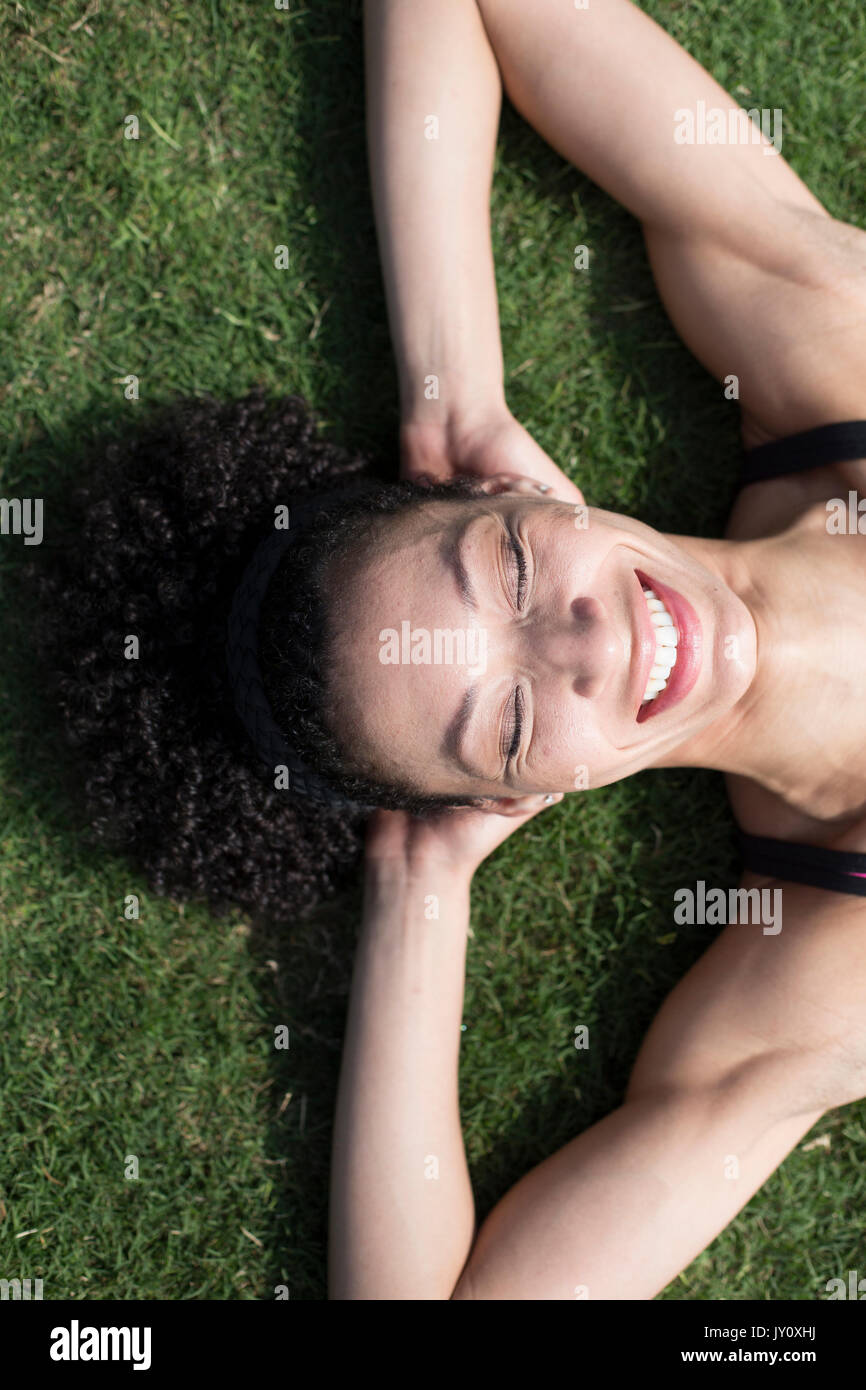 Mixed Race woman laying on grass relaxing, Stock Photo