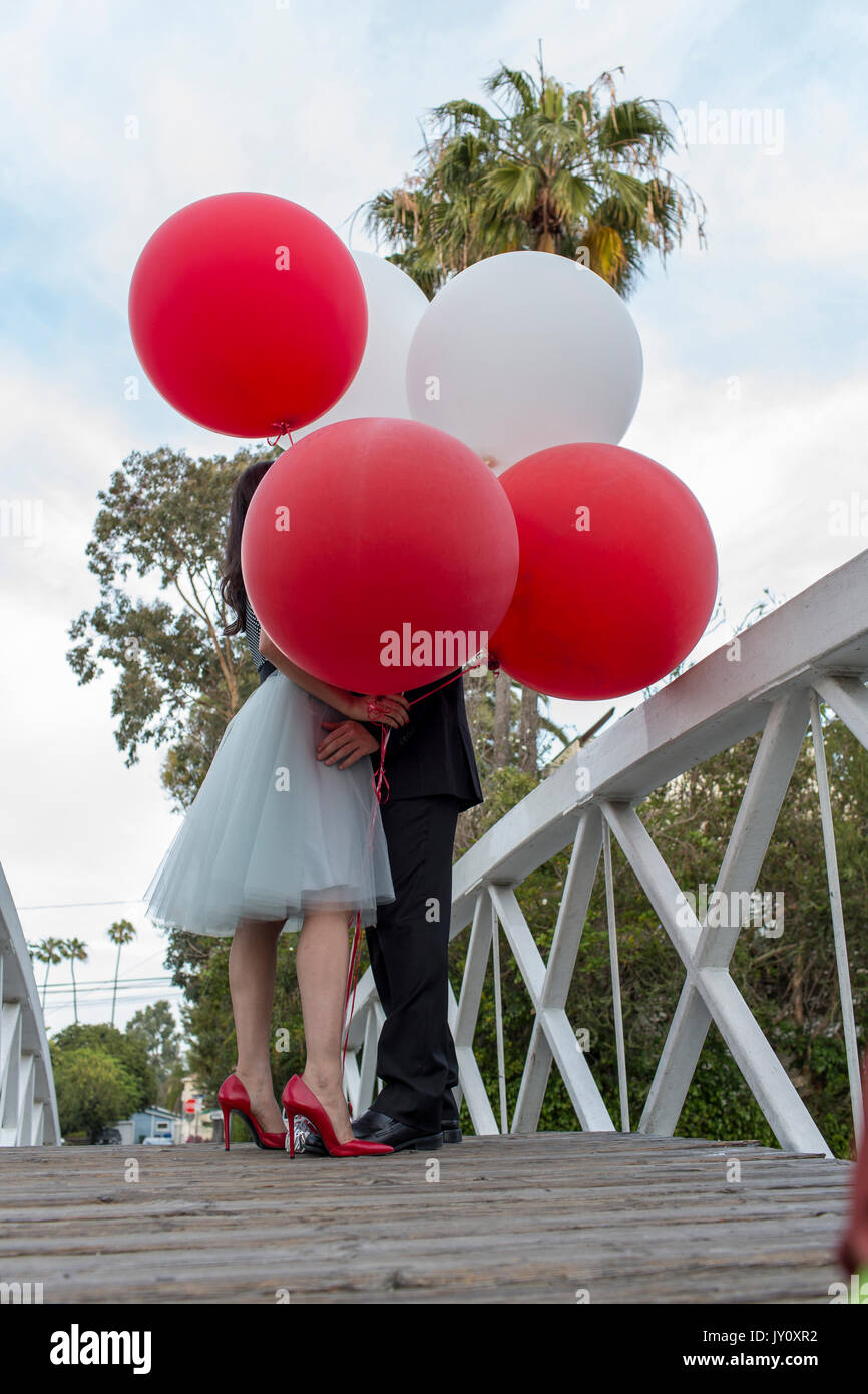 Couple on bridge kissing behind balloons Stock Photo