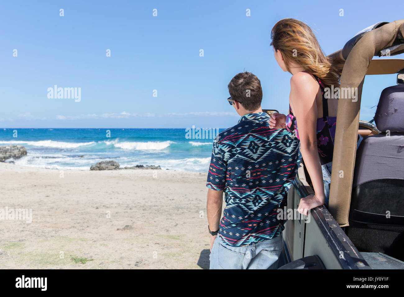 Couple leaning on convertible car at beach Stock Photo