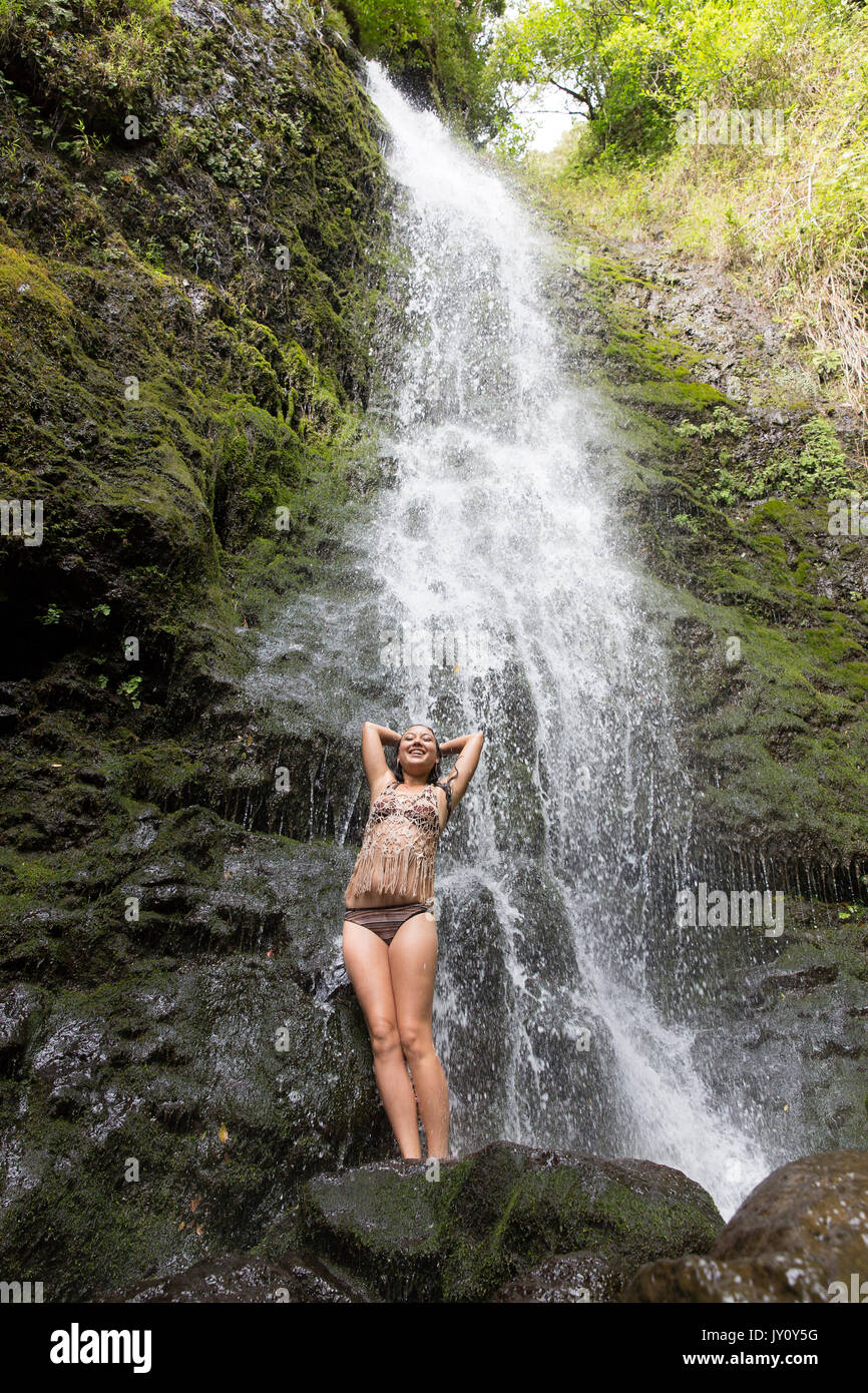Caucasian woman standing on rock near waterfall Stock Photo