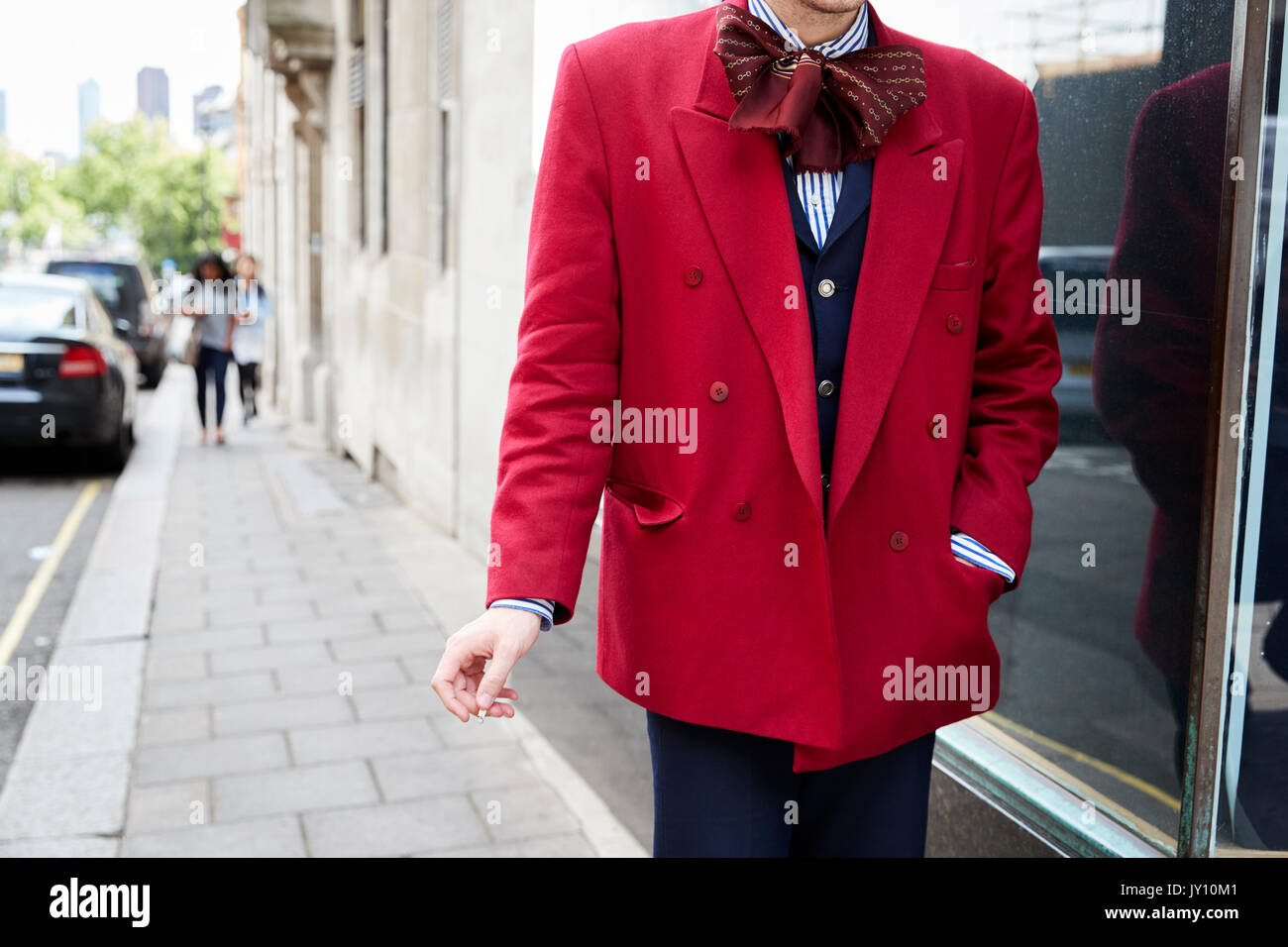 Man in red jacket over blue suit and bow scarf, mid section Stock Photo
