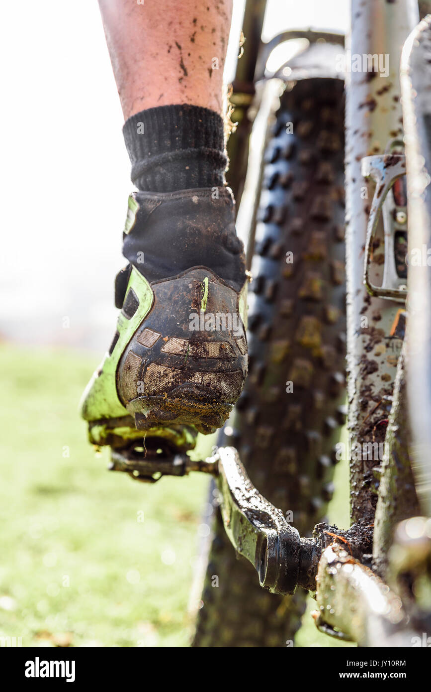 Leg of Caucasian man splattered in mud riding bicycle Stock Photo