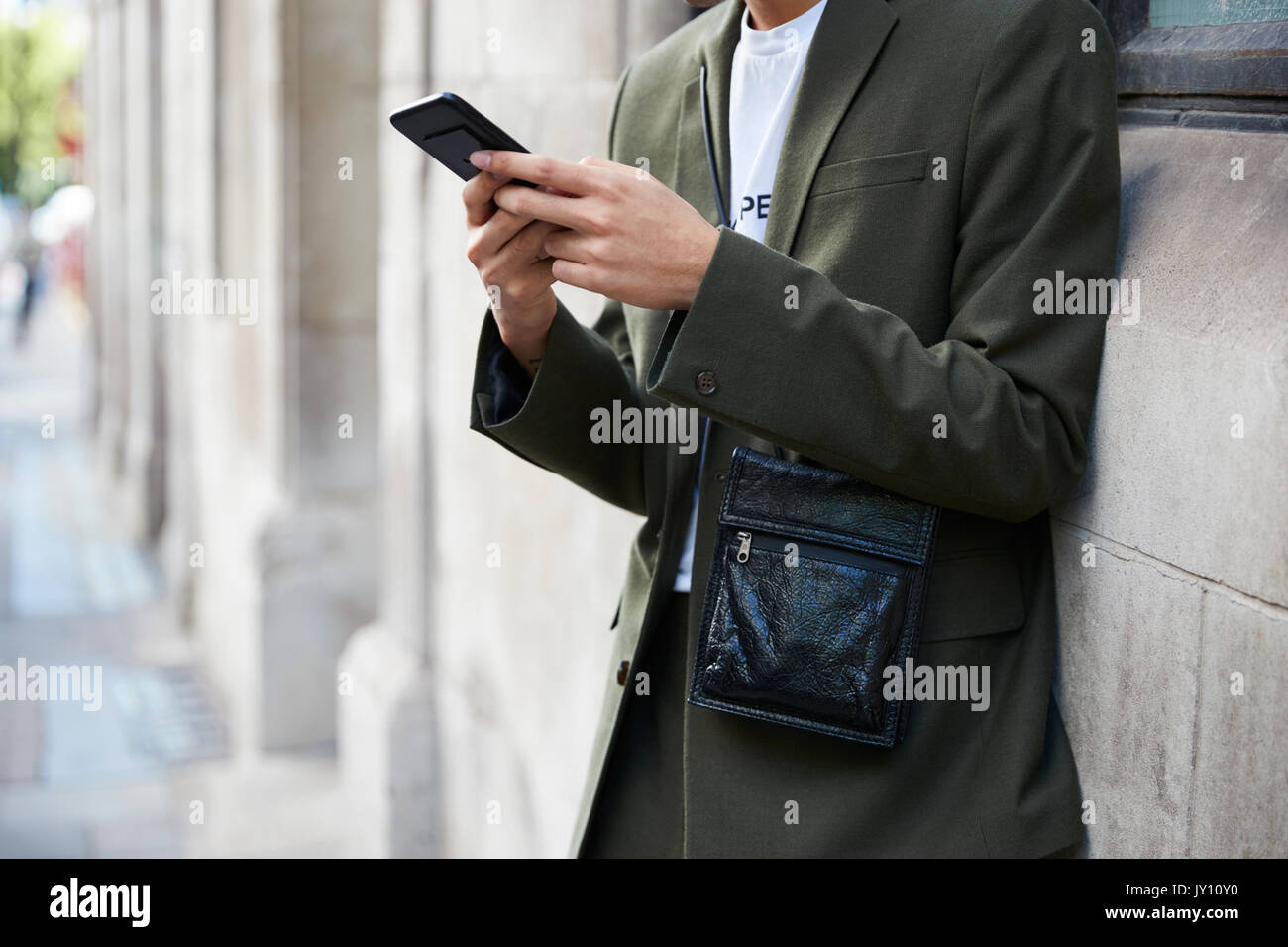 Man in dark green suit using smartphone, mid section Stock Photo