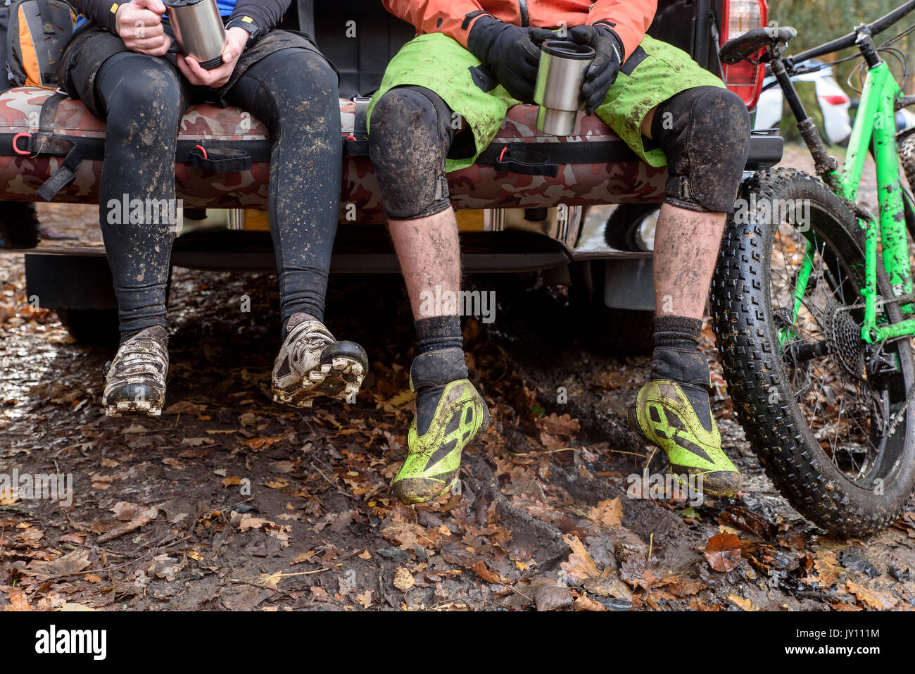 Legs of Caucasian couple sitting in pickup truck near bicycle Stock Photo