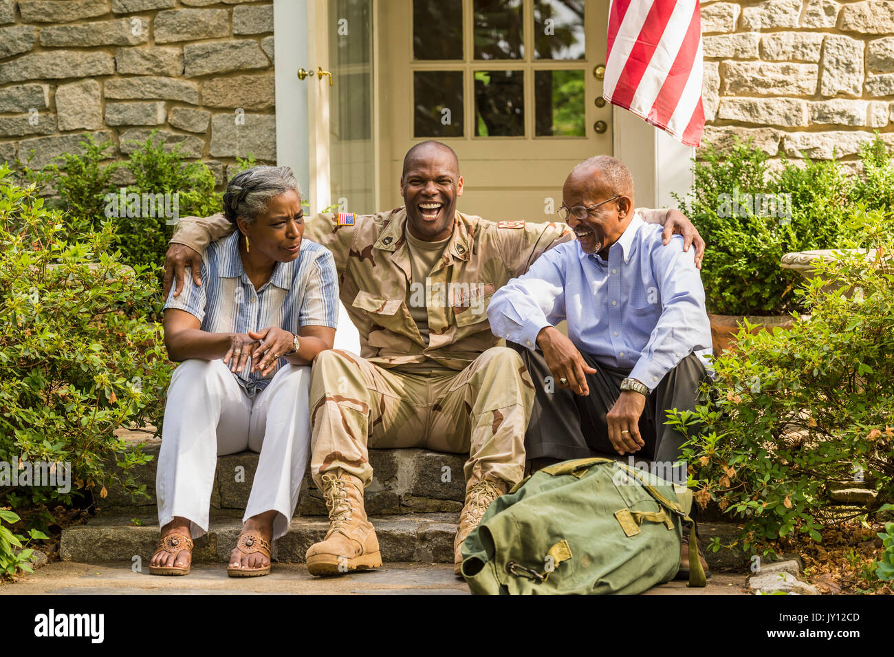 Soldier sitting on front stoop with parents Stock Photo