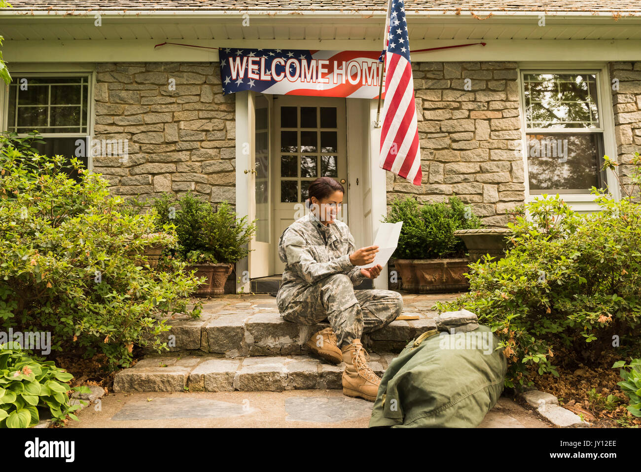 Smiling African American soldier sitting on front stoop reading letter Stock Photo