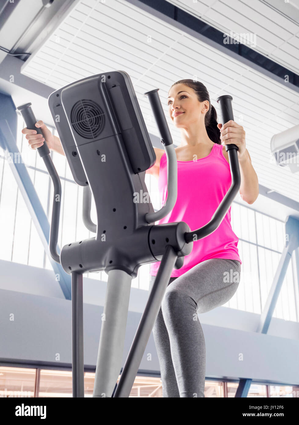 Caucasian woman using elliptical machine in gymnasium Stock Photo