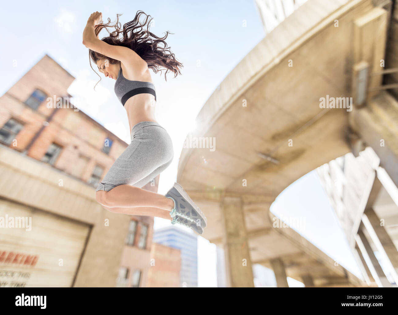 Caucasian woman jumping in city Stock Photo
