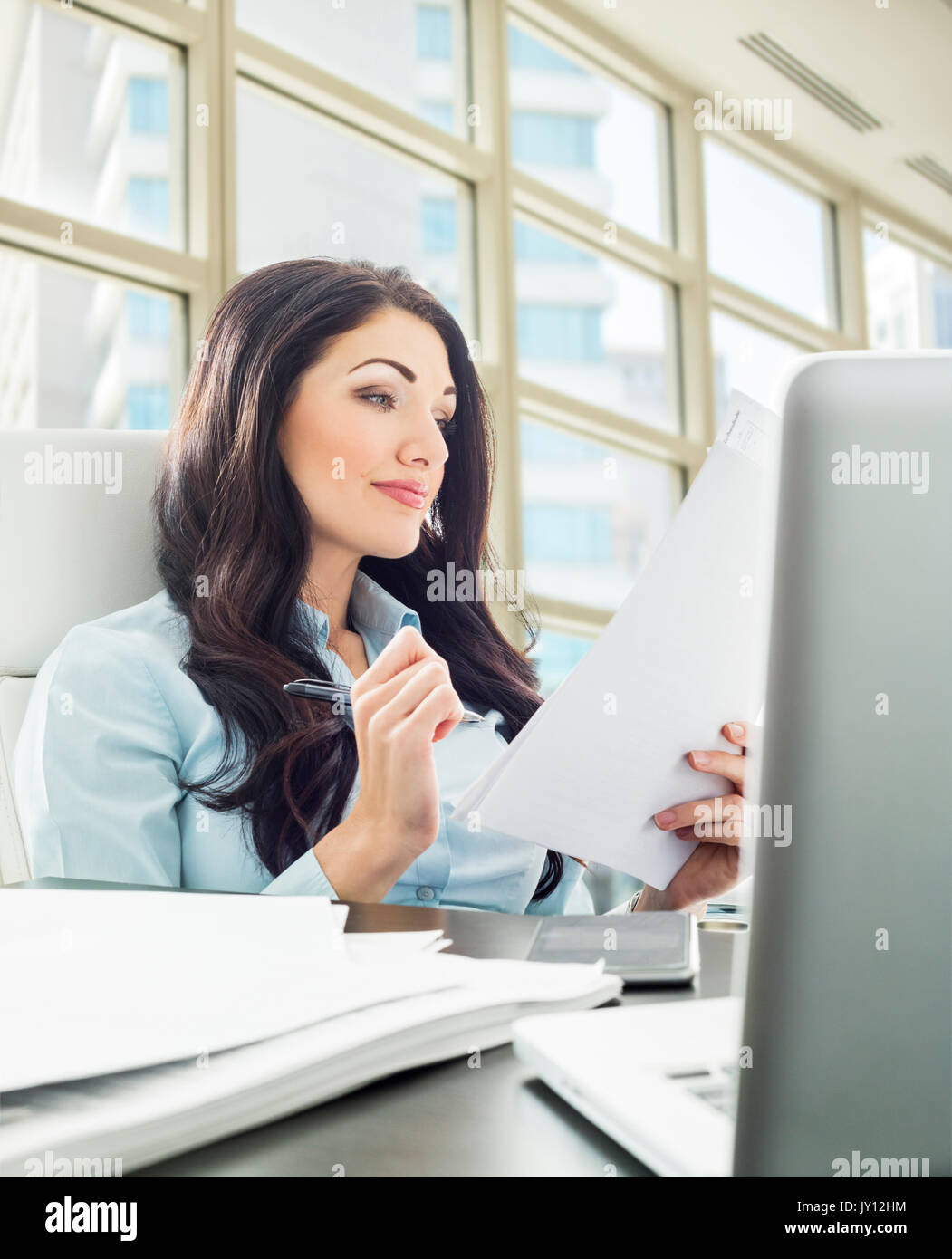 Caucasian businesswoman reading paperwork Stock Photo