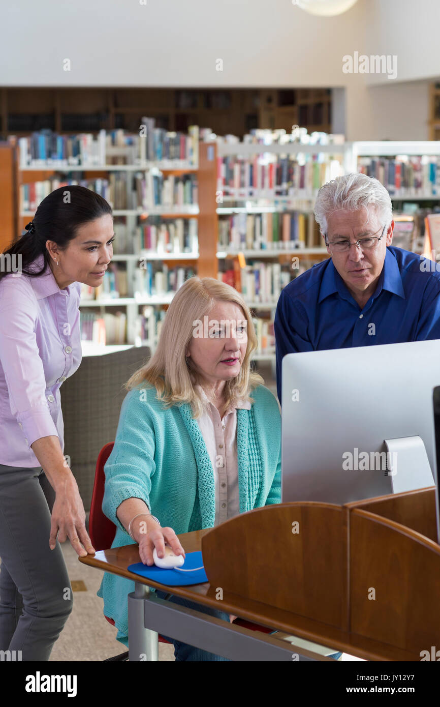 Older people using computer in library Stock Photo