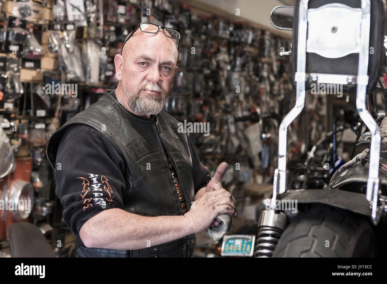 Caucasian man repairing motorcycle and wiping hands Stock Photo