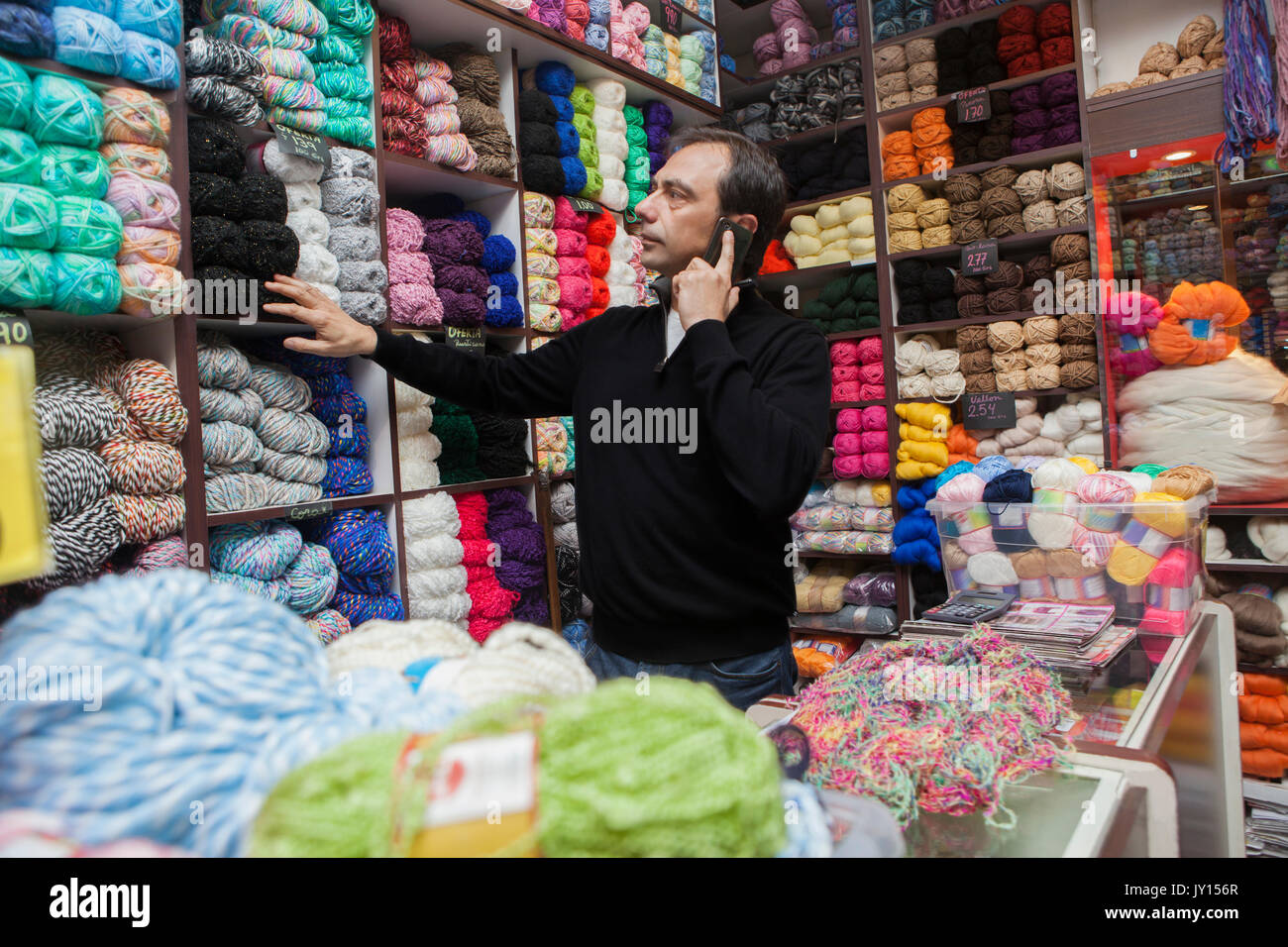 Mixed Race man talking on cell phone at yarn store Stock Photo