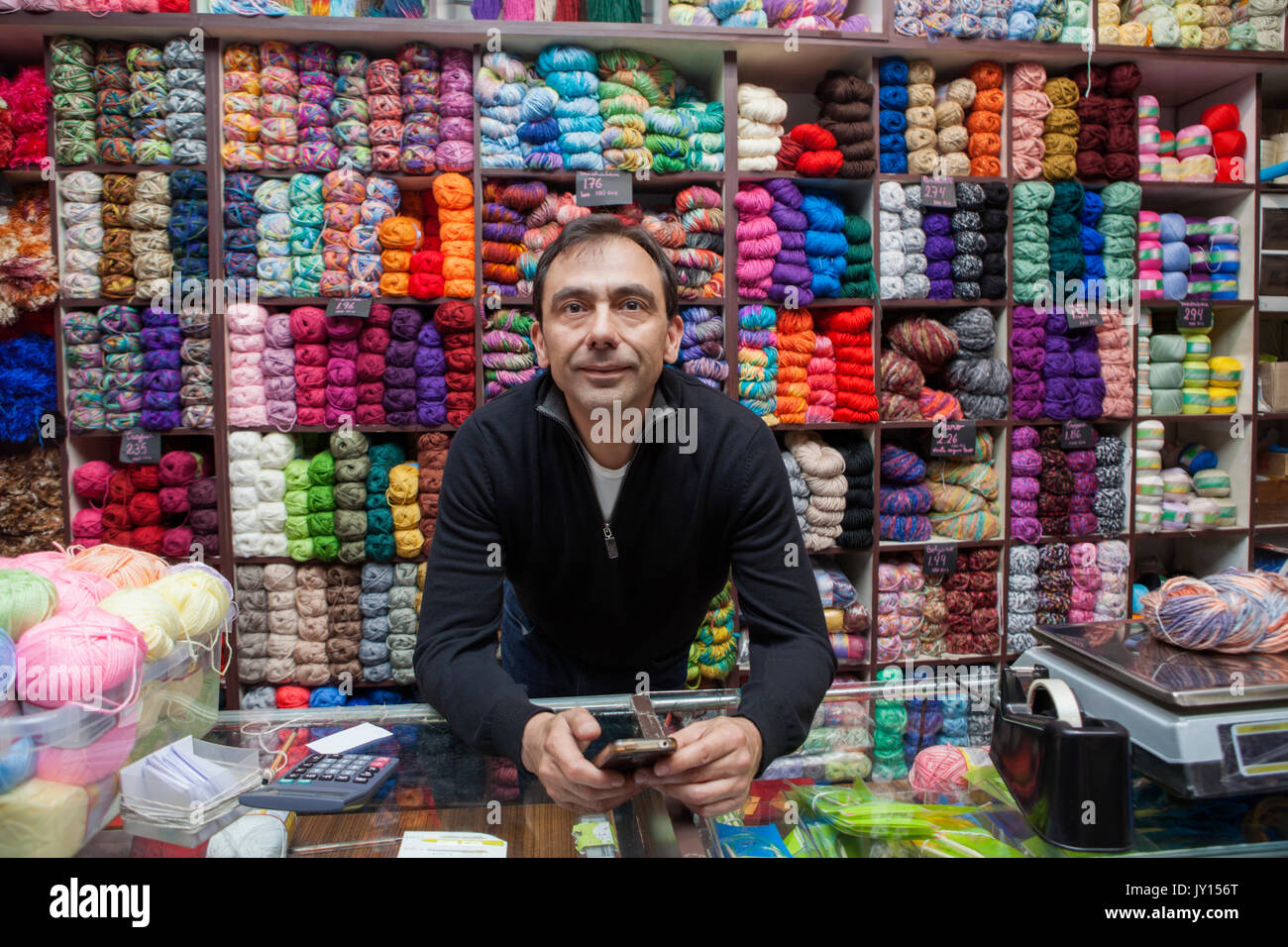 Mixed Race man texting on cell phone at yarn store Stock Photo