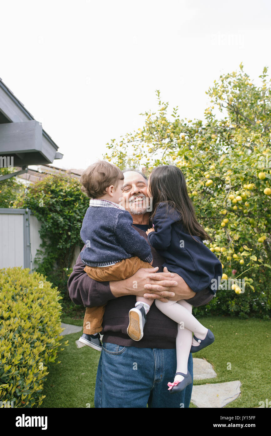 Boy and girl kissing grandfather Stock Photo