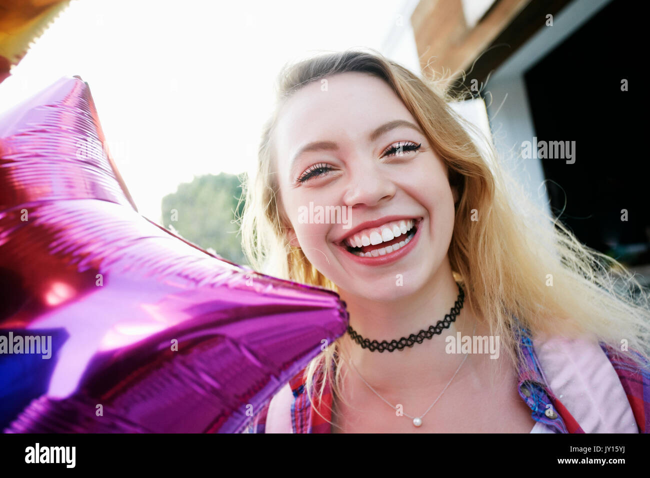 Portrait of Caucasian woman laughing and holding balloon Stock Photo