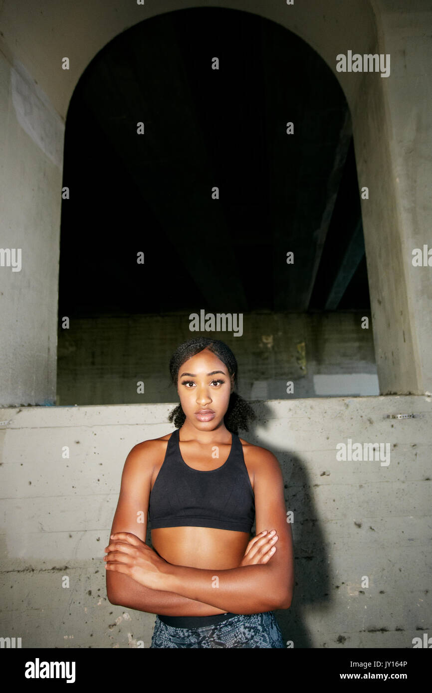 Mixed Race woman with arms crossed under overpass Stock Photo