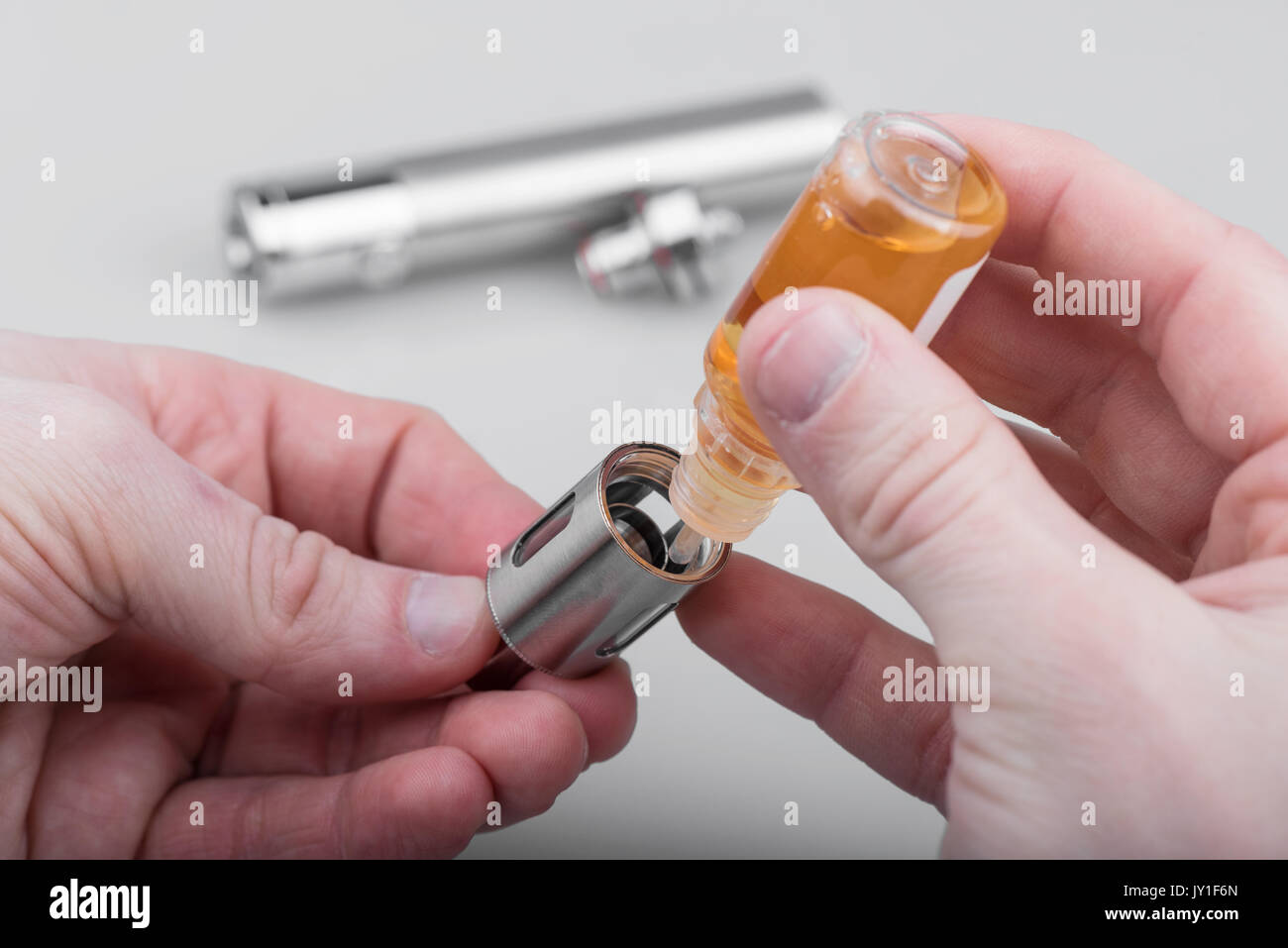Human hands filling e-cig atomizer with e-liquid Stock Photo