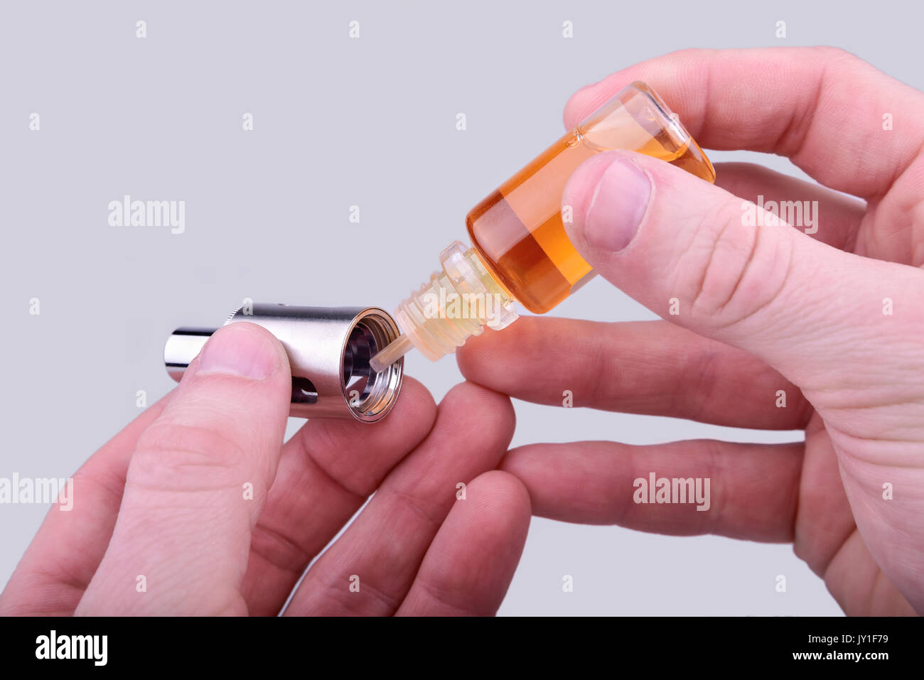 Human hands shows how to fill e-cig atomizer with e-liquid Stock Photo