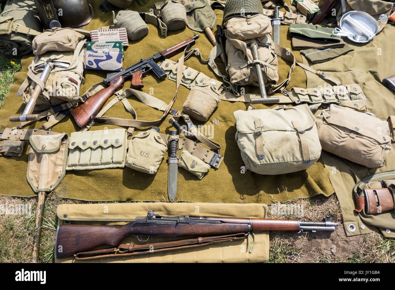 WW2 US soldier outfit and weapons displayed on the ground at World War Two militaria fair showing M1 Garand rifle and Thompson submachine gun Stock Photo