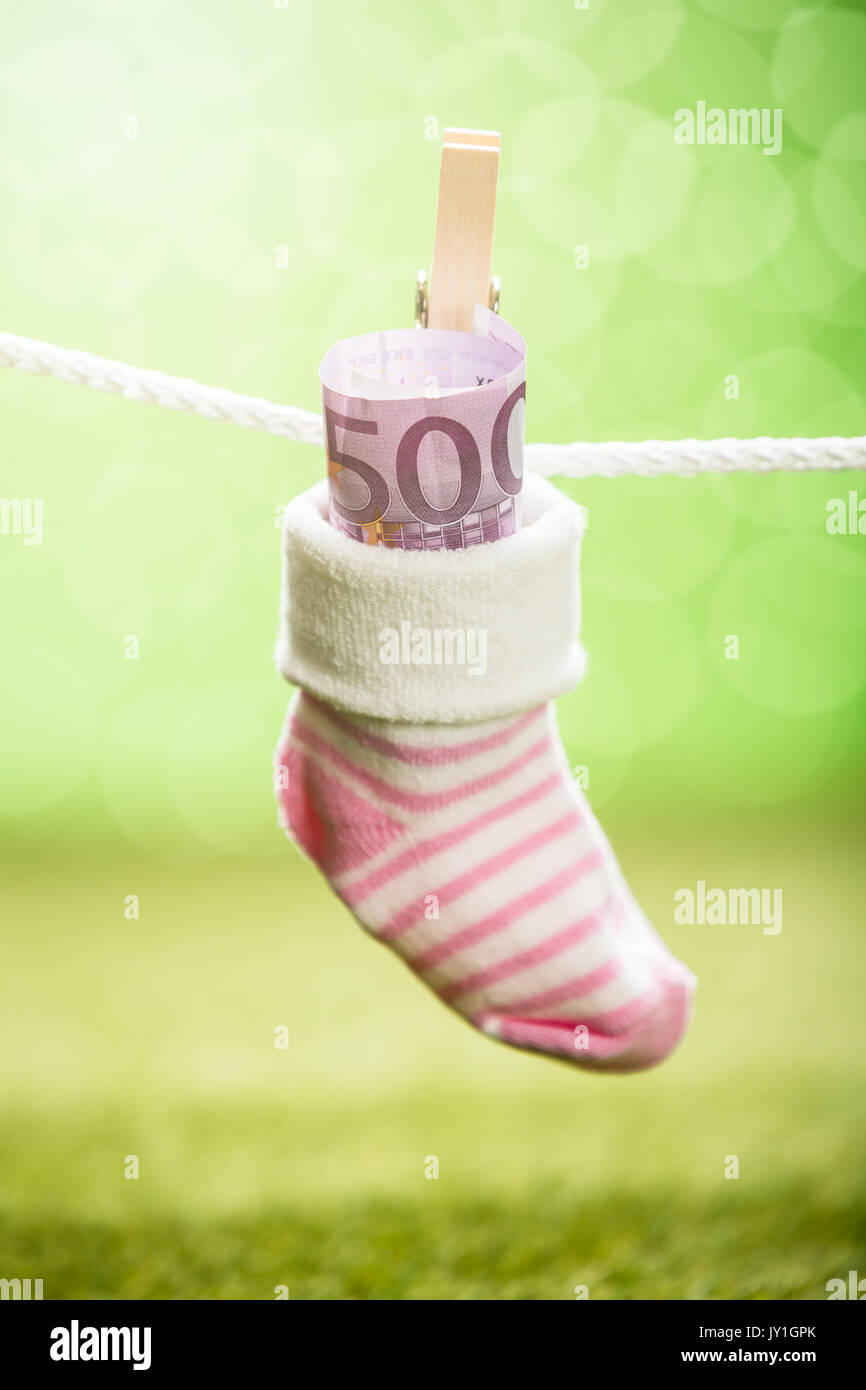 Baby Sock With Dollar Hanging On Rope Using Wooden Clip Stock Photo