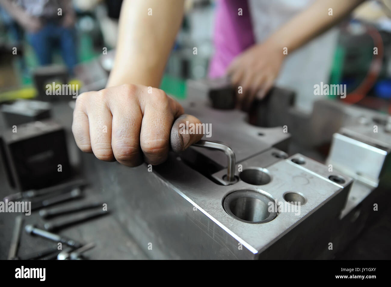 Worker's hand screwing while working with press form Stock Photo