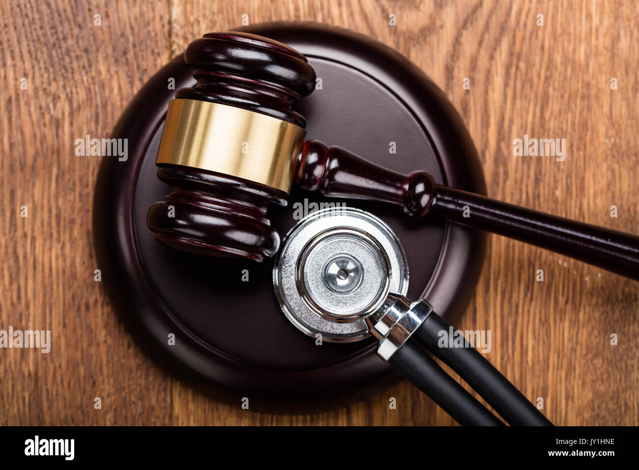 High Angle View Of Brown Gavel With Medical Stethoscope At Wooden Desk In Courtroom Stock Photo