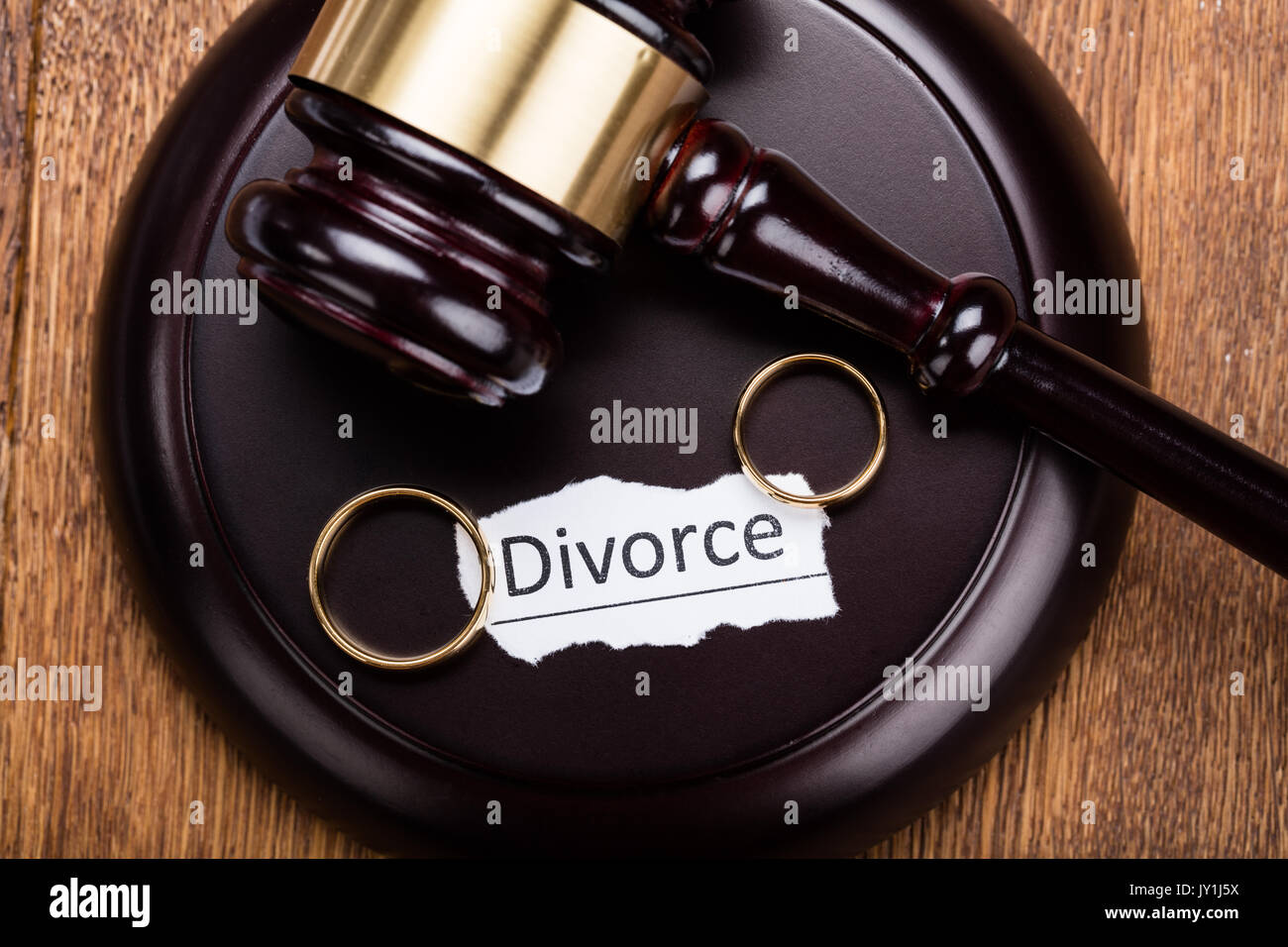 Close-up Of Wedding Rings On Wooden Mallet At Table In Courtroom Stock Photo
