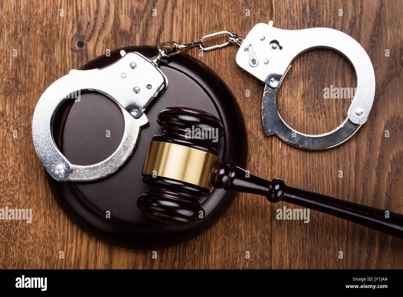 High Angle View Of Judge Gavel And Handcuffs On Wooden Desk Stock Photo