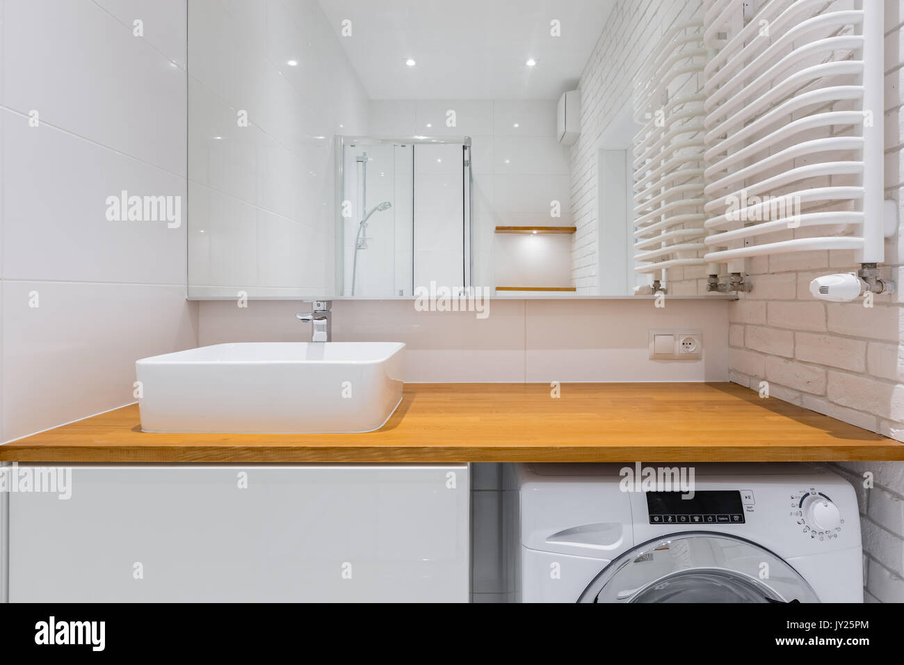 Bathroom with wooden countertop, mirror, shower and washer Stock Photo