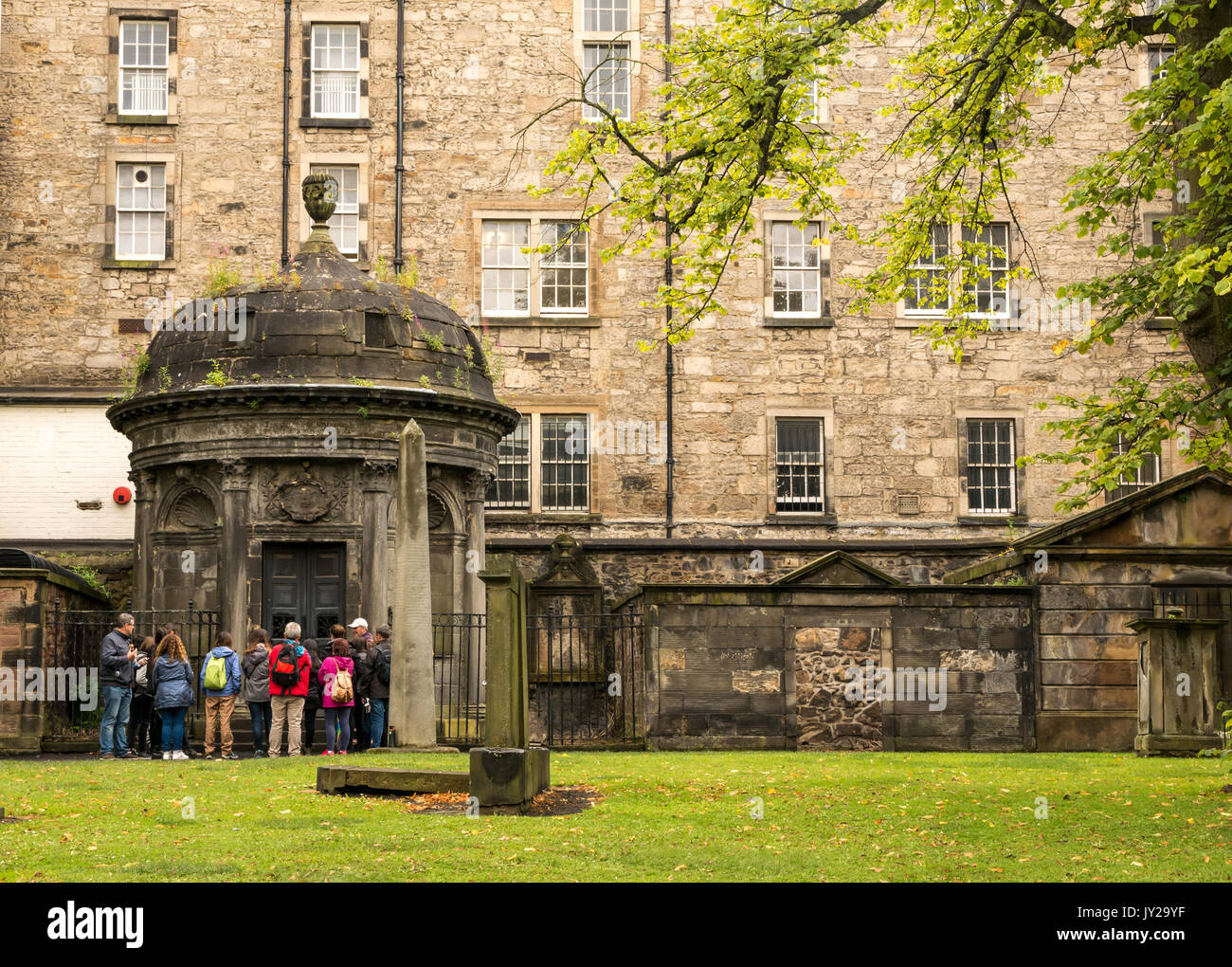 Group of tourists with guide visiting historical Greyfriar's churchyard, Candlemaker Row, Edinburgh, Scotland, UK, admiring the old tombs Stock Photo