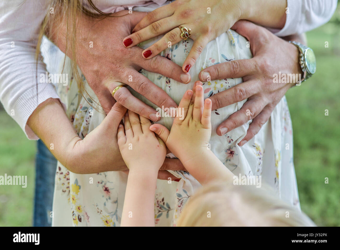 Hands of female male and baby make heart shape cute sign on bare belly ...